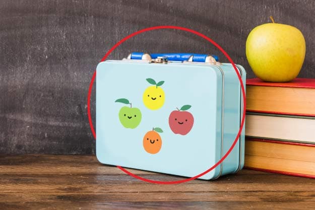 imagen blog vital: Recetas divertidas para una lonchera saludable (lonchera azul con calcomanias de frutas al lado de libros)
