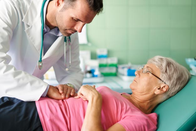 Médico examinando estómago a paciente mujer mayor de edad 