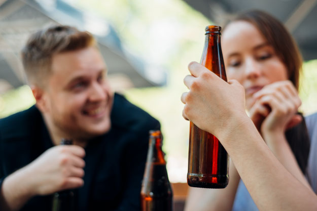 pareja de hombre y mujer con botellas de mano, blog vital efectos del exceso de alcohol